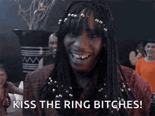 a woman with dreadlocks is holding a ring in her hand and saying `` kiss the ring bitches ! ''