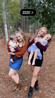 two women holding babies in front of a sign that says 2020 on it