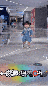 a little girl in a denim dress is standing in a shopping mall with the word boom written on the floor