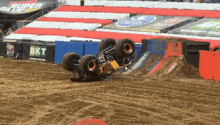 a monster truck is upside down on a dirt track .