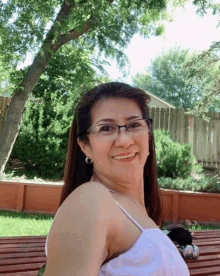 a woman wearing glasses and a white top smiles for a picture