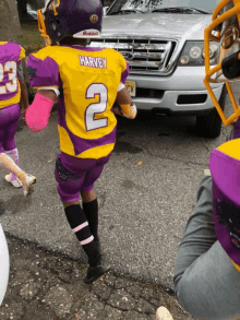 a kid wearing a yellow and purple football uniform with the number 2 on it