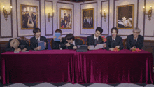 a group of men are sitting at a table with a laptop and a magazine that says nct