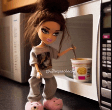 a bratz doll is standing in front of a microwave with a cup of noodles in it