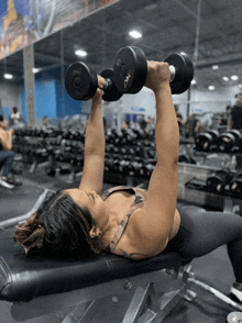 a woman is lifting dumbbells in a gym and the dumbbells have the letters g on them