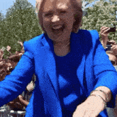a woman in a blue jacket is standing in front of a crowd of people .