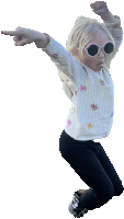 a little girl wearing sunglasses and a white shirt with flowers on it is jumping in the air