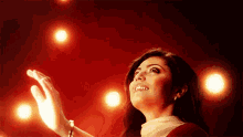 a woman in a red and white dress is looking up at the lights