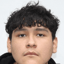 a close up of a man 's face with curly hair and a black hoodie .