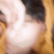 a blurred image of a person 's face with a yellow background