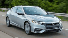 a gray honda insight is driving down a highway .