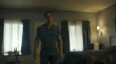 a man in a grey shirt is standing in a motel room