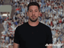 a man in a black shirt is standing in front of a crowd with a state farm logo on his shirt