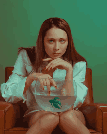 a woman is sitting in a chair holding a fish bowl