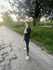 a girl wearing a black shirt and white crocs stands on the side of a road