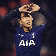 a soccer player wearing a jersey that says aia makes a heart with his hands