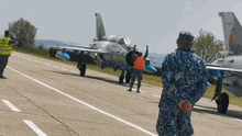 a man in an orange vest is standing in front of a plane with the letters nc on the tail