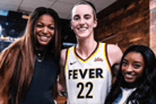 three women are posing for a picture with a basketball player in a fever 22 jersey .