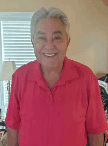 a man wearing a red polo shirt is smiling for the camera