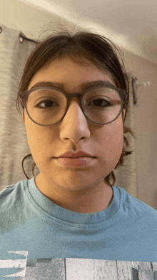 a girl wearing glasses and a blue shirt with a picture of a building on it