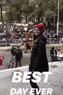 a woman in a red hat stands in front of a crowd with the words " best day ever " on the bottom