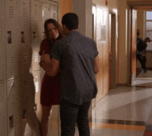 a man and a woman are hugging in a hallway with lockers that say ' a ' on the front