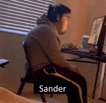 a man wearing headphones sits in a chair in front of a computer monitor with the name sander on the bottom right