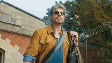 a man wearing sunglasses and carrying a briefcase walks in front of a building that says prison