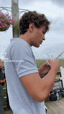 a young man with curly hair is holding a cup with a straw in his hand while standing on a deck ..