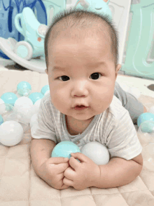 a baby is laying on his stomach playing with balls on the floor