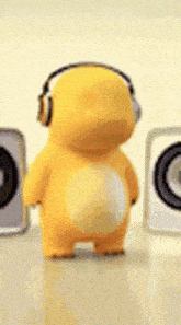 a yellow stuffed animal wearing headphones is standing in front of speakers