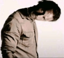 a man wearing sunglasses and a shirt is standing with his head down .