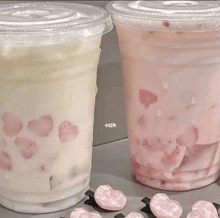 two plastic cups of milk with hearts on them are sitting on a table .