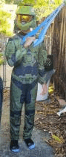 a young boy in a halo costume is holding a toy sword .