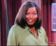 a woman in a green striped shirt is smiling while standing in a room .