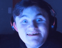 a young boy wearing headphones is making a funny face in front of a computer screen .