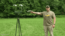 a man is holding a gun in a field and wearing a shirt that says ' the wright ' on it