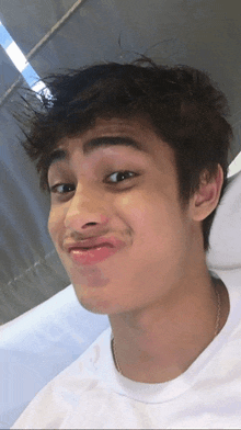 a young man in a white shirt is making a face