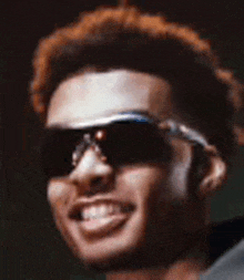 a man wearing sunglasses and a headband is smiling .