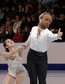 a man and a woman are dancing on the ice in front of a crowd