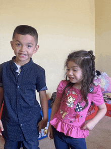 a boy and a girl are standing next to each other and the girl is wearing a pink shirt that says strawberry shortcake