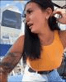 a woman in a yellow tank top and hoop earrings is crying while sitting on a boat .