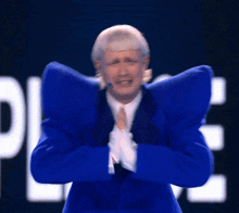 a man in a blue suit with huge shoulder pads is praying