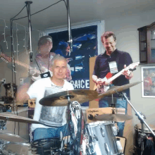 a man playing a drum set in front of a sign that says raices