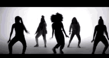 a group of women are dancing in a row in silhouette .