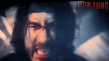 a close up of a man 's face with the words iron lung in red behind him