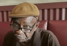a man wearing glasses and a hat is sitting on a couch
