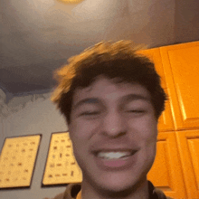 a close up of a man 's face smiling in front of a wall with alphabet signs