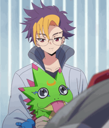 a boy with glasses holds a stuffed animal with a green head