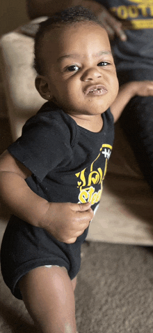 a baby wearing a black shirt with a bottle of soda on the front